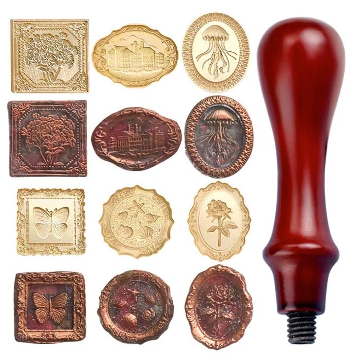Thirteen-piece vintage wax seal kit with a burgundy wooden handle, six interchangeable brass stamp heads, and bronze wax impressions.